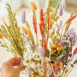 Load image into Gallery viewer, Sustainable dried wildflower bouquet featuring lavender, cornflowers, bunny tails. orange strawflowers, yellow yarrow, and preserved roses on a white surface. Plastic-free, long-lasting arrangement with rustic wheat stems and a natural tag. Perfect eco-friendly home décor from our forever-lasting collection. Birthday UK. Housewarming present when you don't know what to buy. Lavender & Peach flower bunch bouquets. Flowers for birthdays. Long lasting flowers. Dried flower bouquets