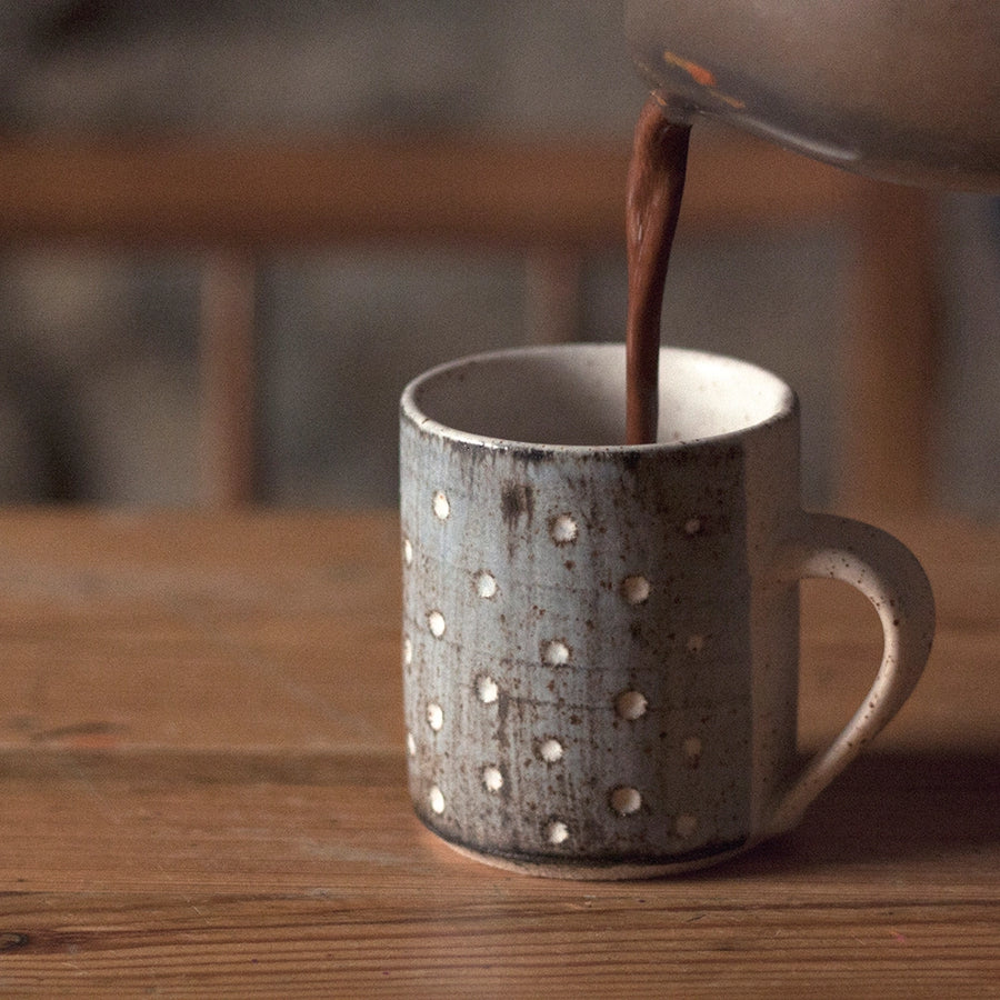 Hands pouring creamy Harth hot chocolate into ceramic mug, steam rising - luxury vegan hot chocolate