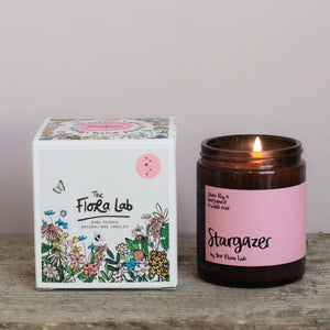 Stargazer Natural Candle. Our candles are all hand poured with natural plant based wax. Hand poured in the UK and poured in a brown amber glass by our female owned team. Long lasting candles that fully scent a room. Our candles are complete with a gold alliminium lid and then packaged in a beautiful botanical box, which features candle safety instructions in a cottage core theme. They are long lasting candles, rated excellent on Trust Pilot and fully scent a room. 