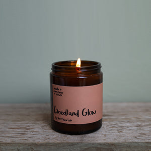 Velvety chocolately woods are the notes that make this winter warmer candle so popular. Unisex, appealing to both men and women, this scent is perfect for Autumn. It is great for the bedroom. Features warming notes such as chocolate, vetiver, warm spices, and nutmeg.  Woodland Glow single Wick Long Lasting Candle being lit by a luxury match 