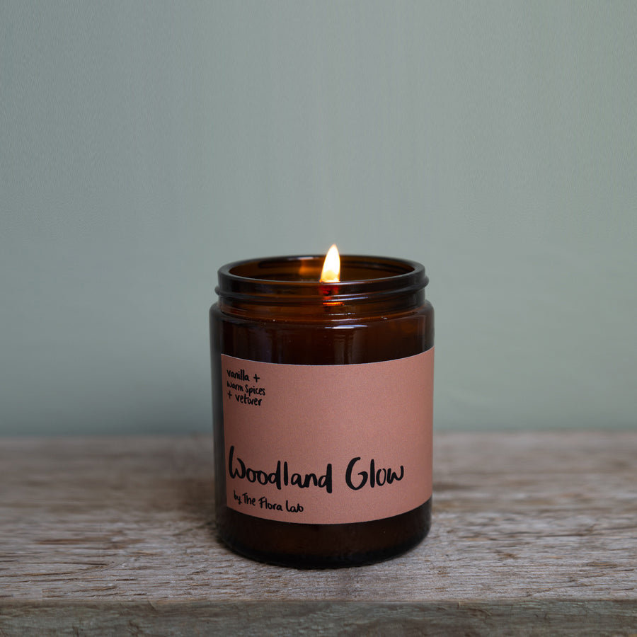 Velvety chocolately woods are the notes that make this winter warmer candle so popular. Unisex, appealing to both men and women, this scent is perfect for Autumn. It is great for the bedroom. Features warming notes such as chocolate, vetiver, warm spices, and nutmeg.  Woodland Glow single Wick Long Lasting Candle being lit by a luxury match 