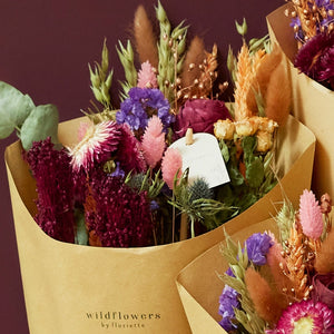 Close up of a dried wild flower bouquet featuring plants such as eucalptyus, rose, thistles, yellow roses. 