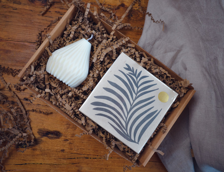 The Light Lovers candle box featuring an unscented soy wax natural-wax pillar candle and a box of letterpress matches in a sustainanly made gift box. 